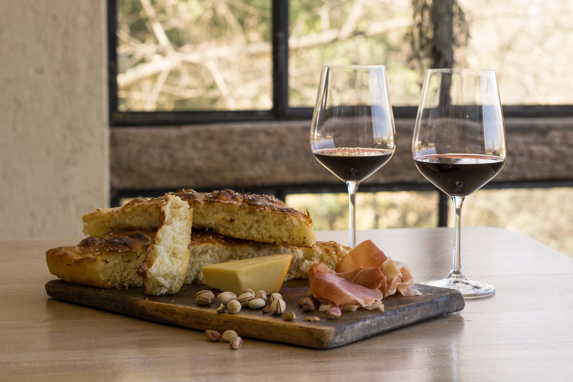 View of a wooden board Focaccia, ham cheese, wine and pistachio