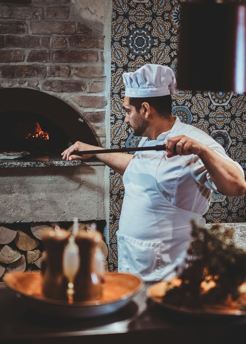 Chef is putting pizza to the oven